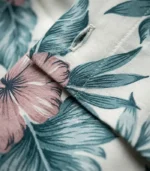 Close-up of cream viscose fabric with teal palm leaf and dusty pink hibiscus tropical floral print